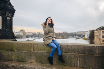 Smiling tourist woman in Prague speaking on smartphone. Young woman tourist stands on the Charles Bridge in Prague in the Czech Republic uses phone