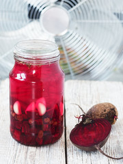 Beet kvass (juice) in a glass jar. Fermented drinks. Nearly cut beet tubers. Located on a wooden white background. Close-up.