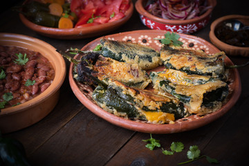 Chilles rellenos served in traditional mexican dishes, served with beans, pickles