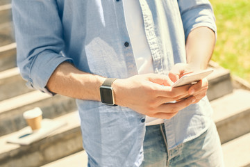 Outdoors Leisure. Stylish guy wearing watch walking on stairs in park browsing smartphone close-up