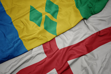 waving colorful flag of england and national flag of saint vincent and the grenadines.