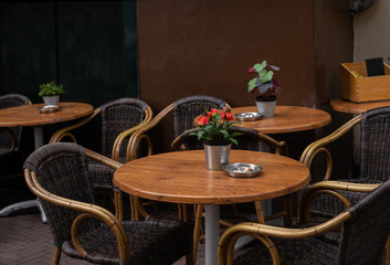 Fototapeta na wymiar Cafe on the street, empty chair and table of cafeteria, flowerpot of cyclamen, ashtray for cigarettes on the table