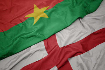 waving colorful flag of england and national flag of burkina faso.