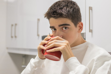 young teenage man having cup of coffee or breakfast at home