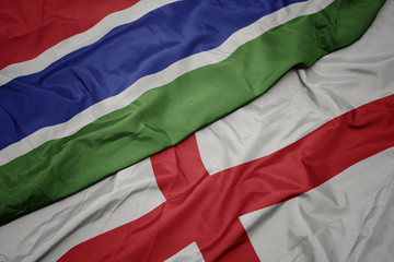 waving colorful flag of england and national flag of gambia.