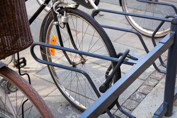Bike locked securely via u-lock in bicycle parking area. Front right side view of front wheel. Security, stolen bike