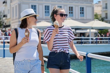 Melting ice cream in hands of smiling walking mother and daughter