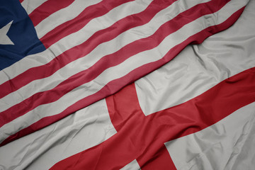 waving colorful flag of england and national flag of liberia.