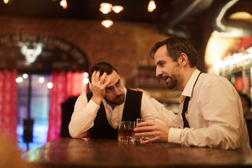 Portrait of two drunk business people talking sitting at table in bar after work, copy space