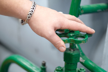 Worker open a valve of pipeline close up background.