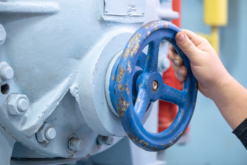 Worker open a valve of pipeline close up background.