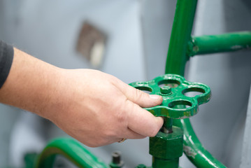 Worker open a valve of pipeline close up background.