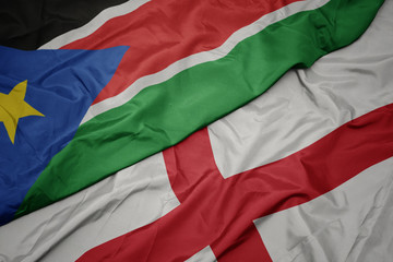 waving colorful flag of england and national flag of south sudan.
