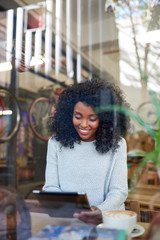 Smiling young African American woman browsing online in a cafe