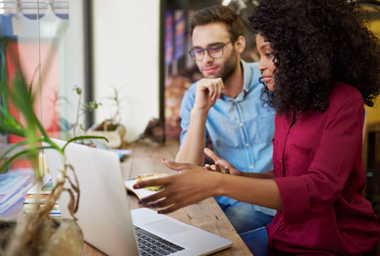 Diverse Young Couple Working On Their Laptop In A Cafe