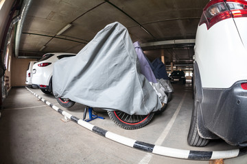 Motorcycles are covered with tents standing on heated parking lot for wintering