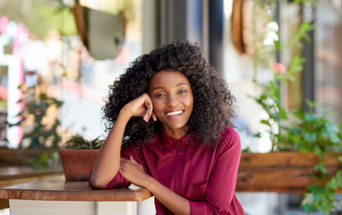 Smiling African American woman sitting outside of her cafe