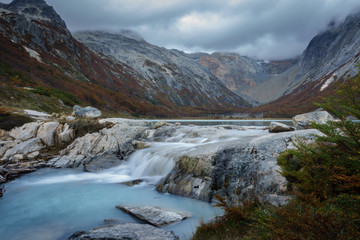 Waterfall of Esmeralda Lake, located in Patagonia Argentina. This place is surrounded by shrubs and turquoise water due to melting of a glacier. The background consists of mountains and clouds.