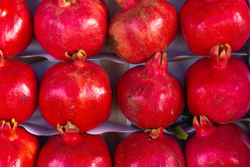 Red pomegranate - Punica granatum - fruits in rows on display for sale. This fruit is full of vitamins and is in season in autumn both in the Northern and Southern Hemispheres. Horizontal photo.