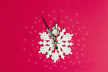 New Year's clock imitation of arrows and snowflakes on a red background. The clock shows midnight. flat lay, christmas background. New Year's composition. Creative background