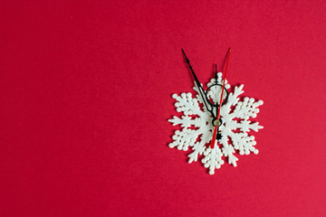Fototapeta premium New Year's clock imitation of arrows and snowflakes on a red background. The clock shows midnight. flat lay, christmas background. New Year's composition. Creative background