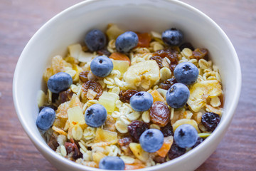 Muesli in the bowl with blueberries, raisins, tropical fruits. Oatmeal on the breakfast.