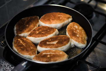 Fried pies in a pan standing on a gas stove