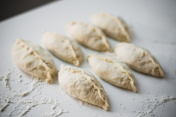 Fototapeta na wymiar Blanks pie on a white table, flour, raw dough