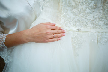 the bride holds in her hands a beautiful wedding dress