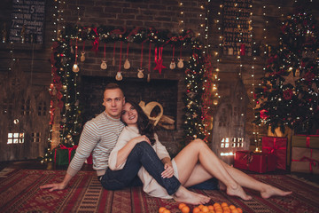 Lovely couple woman and man are lying at home with mandarins. Xmas time.