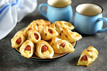 Sausages in puff pastry with mashed potatoes on a dark background.