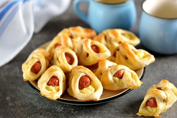 Sausages in puff pastry with mashed potatoes on a dark background.