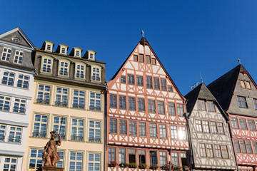 Obraz premium Outdoor sunny view of old town at Römerplatz, historical market square, surrounded with Römerberg, timber medieval German house, and city hall in Frankfurt, Germany.
