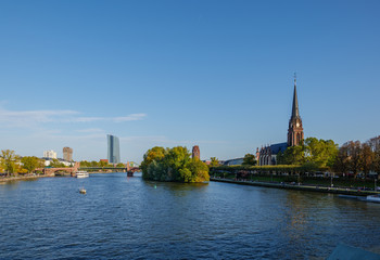Fototapeta premium Outdoor sunny view from Eiserner Steg, Iron Bridge, of promenade on riverside of Main River and background of European Central Bank in sunny day in Frankfurt, Germany.