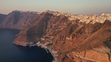 Aerial drone photo of Fira main village of Santorini island with breathtaking views to Caldera and Aegean sea at sunset with beautiful golden colours, Cyclades, Greece