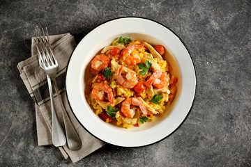 Paella or risotto with chicken breast, shrimp tails, carrots, onions, cherry tomatoes, white wine and chicken stock. Top view. 
