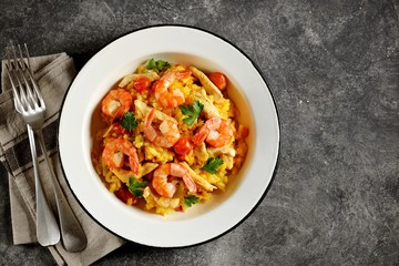 Paella or risotto with chicken breast, shrimp tails, carrots, onions, cherry tomatoes, white wine and chicken stock. Top view. 