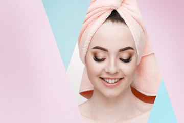Portrait of young beautiful woman with healthy glow perfect smooth skin. Model with natural nude make up with pink towel on head look into the hole of pink, blue paper.