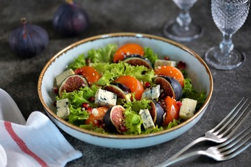 Healthy salad of persimmons, figs, blue cheese, pomegranate seeds, parmesan, lettuce and olive oil.