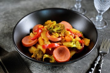 Potato roast with sausages, bell peppers, onions, carrots and broccoli.