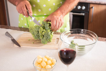Two human hands of a senior man cut and clean the broccoli vegetable. Healthy eating.