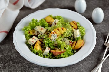 Grilled peach salad with lettuce, blue cheese, parmesan, olive oil and pink pepper.