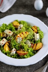 Grilled peach salad with lettuce, blue cheese, parmesan, olive oil and pink pepper.