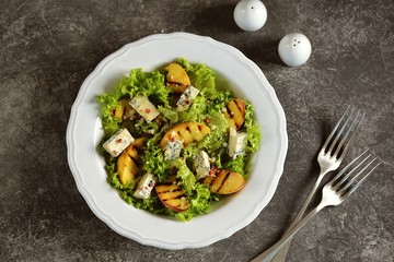 Grilled peach salad with lettuce, blue cheese, parmesan, olive oil and pink pepper.