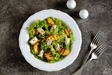 Grilled peach salad with lettuce, blue cheese, parmesan, olive oil and pink pepper.