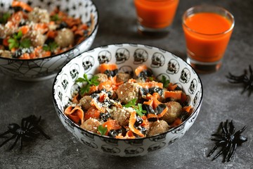 Farfalle Halloween pasta with meat balls and parmesan in a creamy sauce in traditional bowls. Halloween food.
