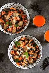 Farfalle Halloween pasta with meat balls and parmesan in a creamy sauce in traditional bowls. Halloween food.