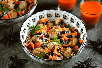 Farfalle Halloween pasta with meat balls and parmesan in a creamy sauce in traditional bowls. Halloween food.