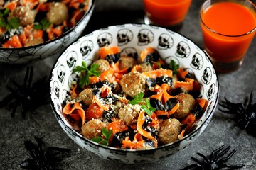 Farfalle Halloween pasta with meat balls and parmesan in a creamy sauce in traditional bowls. Halloween food.