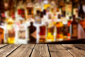 Empty wooden planks against various alcohol bottles in a bar or restaurant. Bar advertisement mockup image